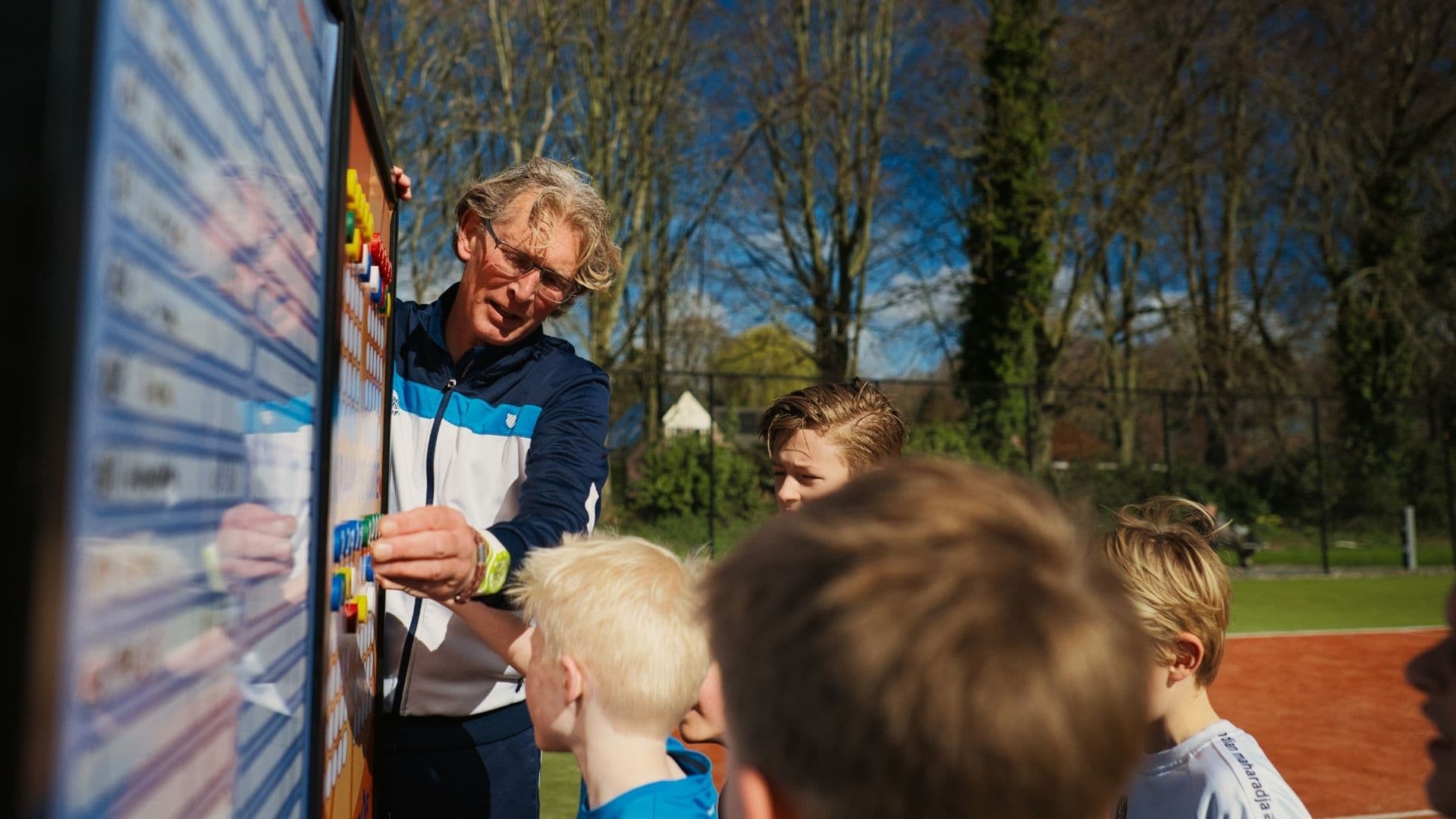 Trainer en kinderen bij het TOF-bord tijdens de les